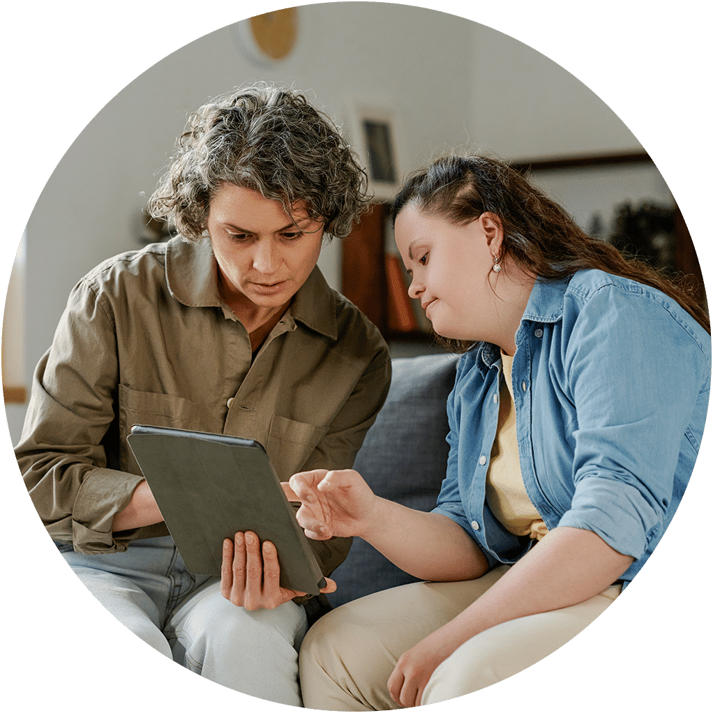 Eine ältere Person zeigt einer jüngeren etwas auf einem Tablet – steht für Wissensweitergabe, Anleitung und generationenübergreifende Zusammenarbeit.